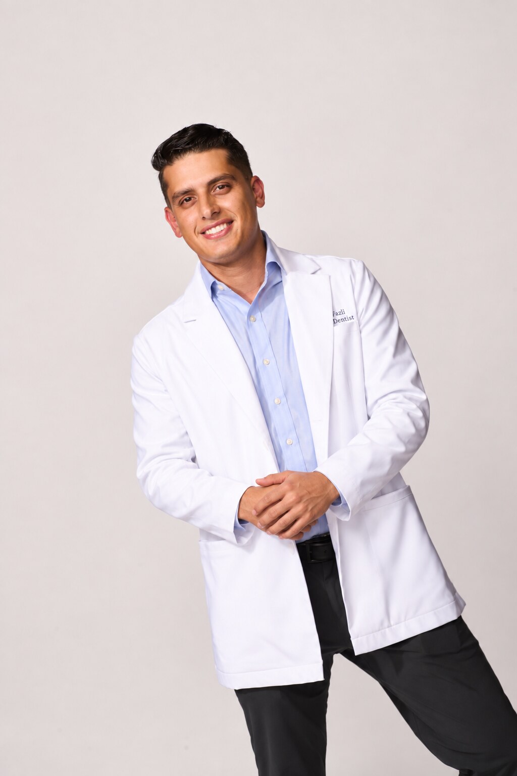 Dr. Fazli smiling in his white dental coat